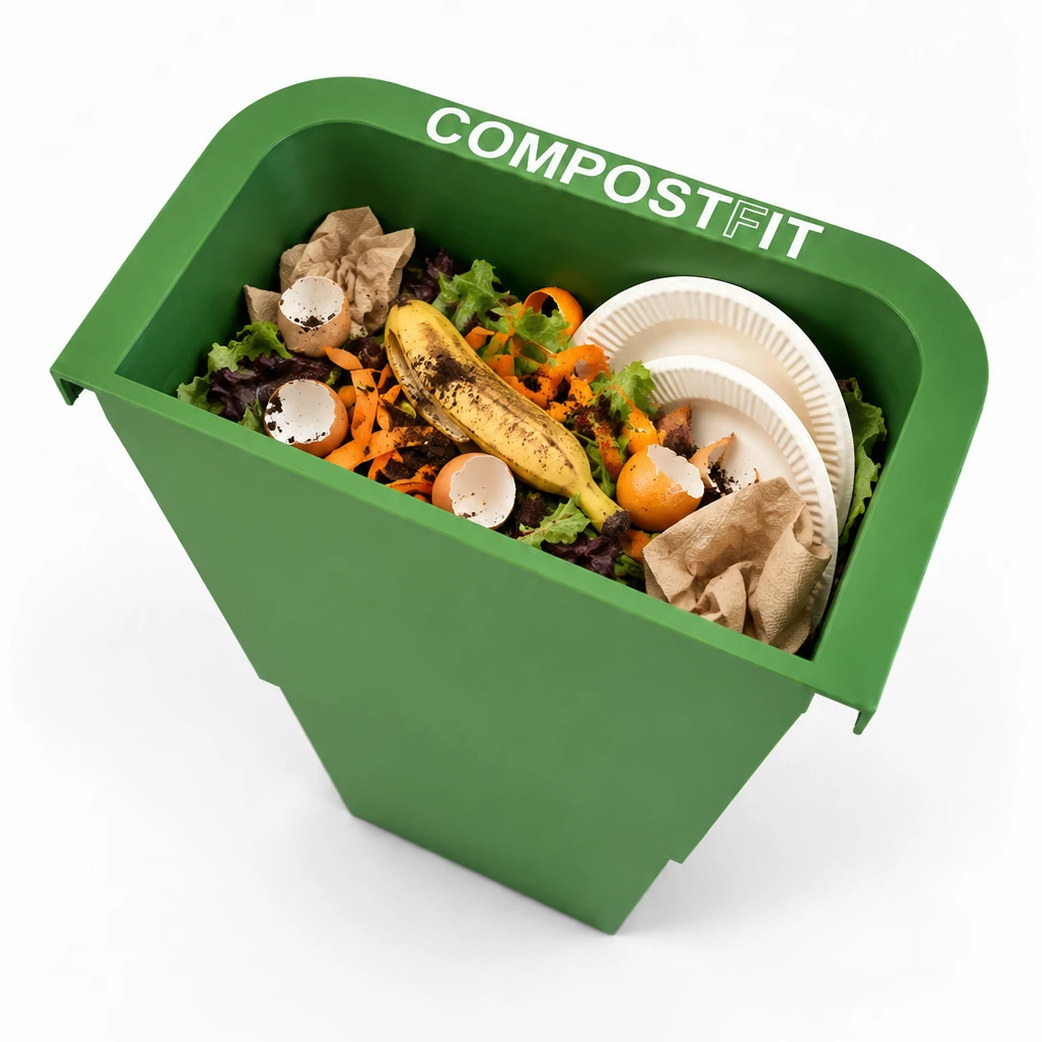CompostFit lifted out of the trash bin, full of food scraps, eggshells, a banana peel, napkins and two paper plates